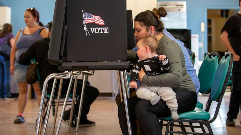 PHOTO: Miranda Padilla holds her 11-month-old son Grayson Sanchez while marking her ballot at a polling center, Nov. 8, 2022, Albuquerque, N.M.