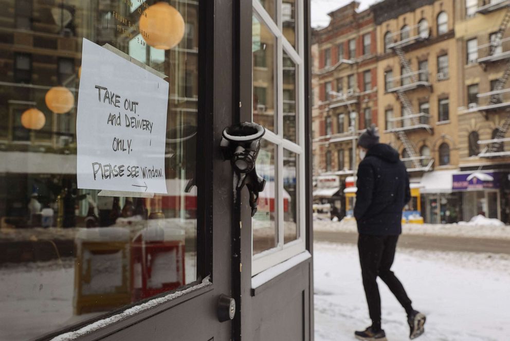 PHOTO: In this Dec. 17, 2020, file photo, a pedestrian walks past a sign reading "Take Out And Delivery Only" on the door of a restaurant in New York.