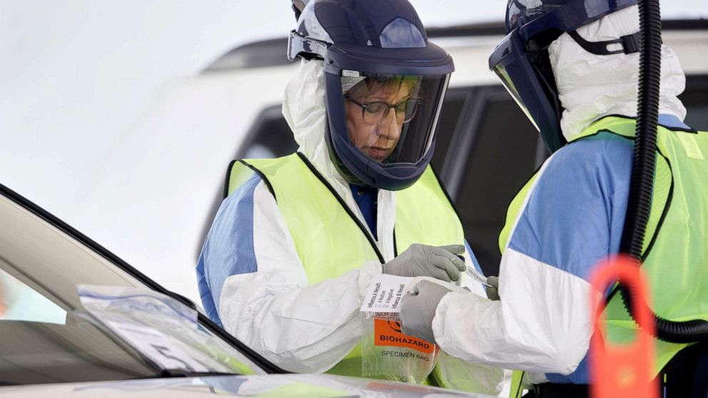 PHOTO: Nurses in protective gear handle a test for the coronavirus at a drive-through testing location at Bryant Health's LifePointe campus in Lincoln, Neb., March 24, 2020. 