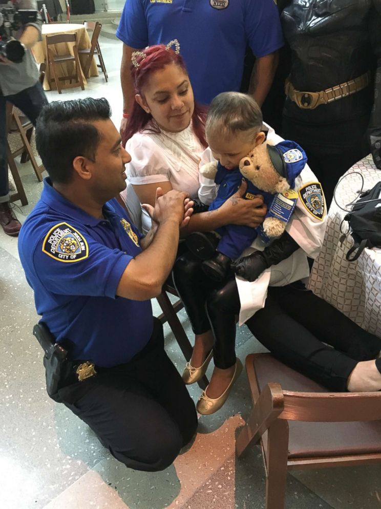 PHOTO: 9-year-old Aniya Ardon sits on her mother's lap as she greets an NYPD police officer at NewYork-Presbyterian Morgan Stanley Children's Hospital. 