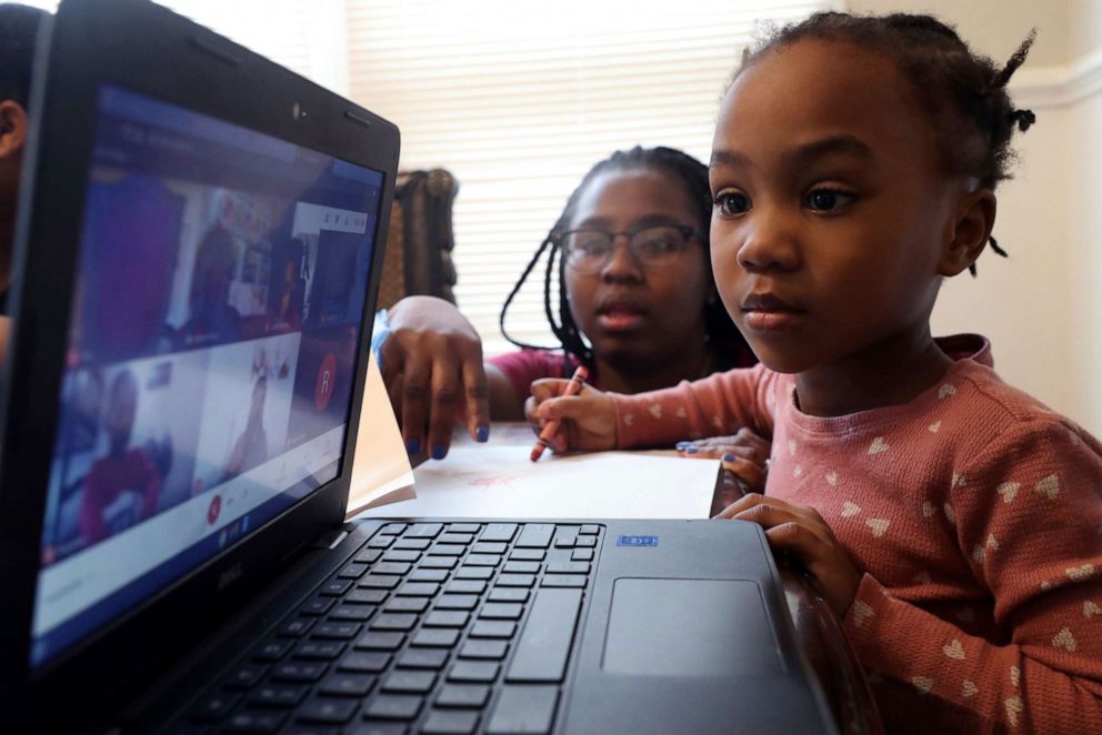 PHOTO: In this Feb. 10, 2021, file photo, Lear Preston, who attends Scott Joplin Elementary School, participates in her virtual classes as her mother, Brittany Preston, background, assists at their residence in Chicago.