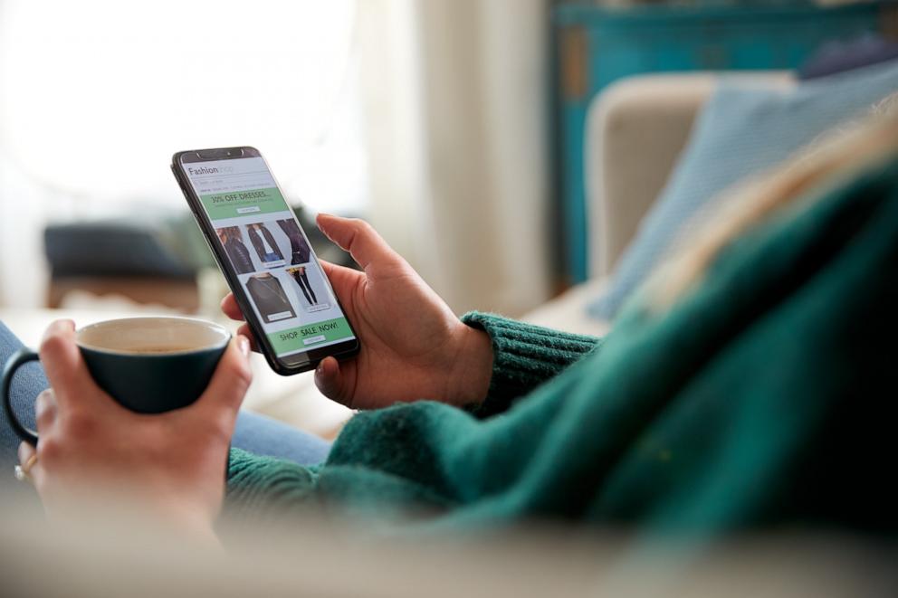 PHOTO: Close up of a woman shopping for clothes online using a mobile phone app.