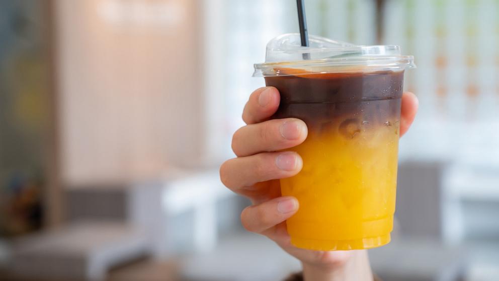 PHOTO: Someone hand holding a cup of Iced Orange Americano.