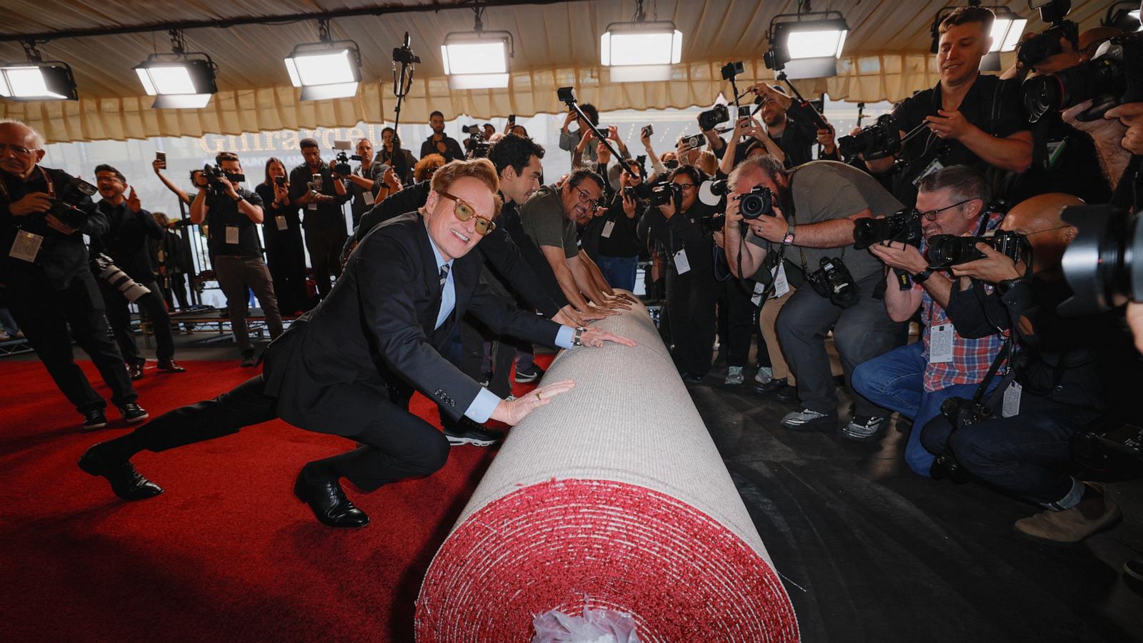 PHOTO: Academy Awards host Conan O'Brien pushes the rolled red carpet during its rollout for the 97th Academy Awards in Los Angeles, Feb. 26, 2025.