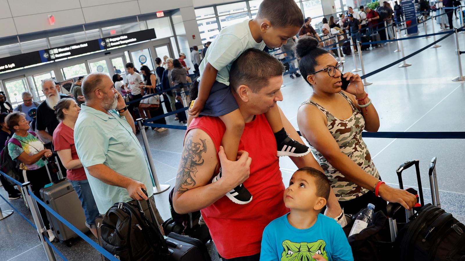 PHOTO: Thomas and Narissa Rahn and their children Jaidon, left, and Jaxon, of El Paso, Texas, wait in line at the Delta terminal after their flight was cancelled, July 19, 2024, at Logan International Airport in Boston.