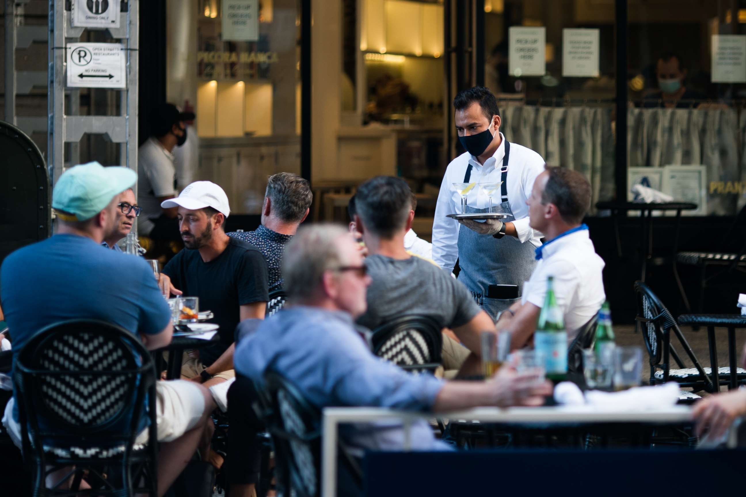 PHOTO: A waiter wearing a protective mask serves drinks outside a restaurant on July 21, 2020, in New York.