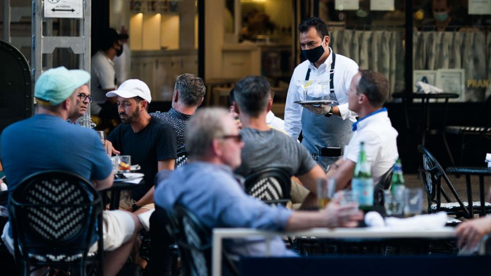 PHOTO: A waiter wearing a protective mask serves drinks outside a restaurant on July 21, 2020, in New York.