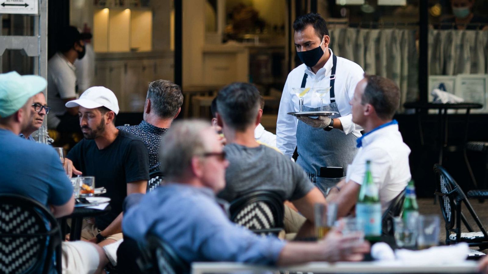 PHOTO: A waiter wearing a protective mask serves drinks outside a restaurant on July 21, 2020, in New York.