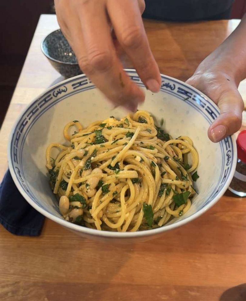 PHOTO: A bowl of spaghetti with sauteed onions, white beans and herbs.