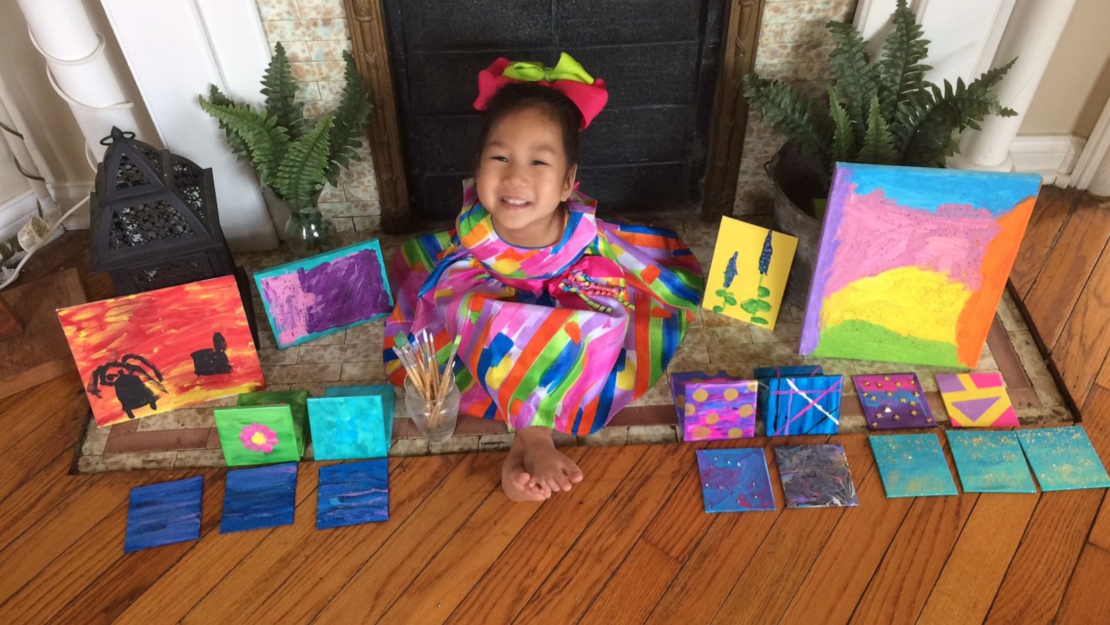 PHOTO: Four-year-old Minh Best sits with the paintings she created with her feet.