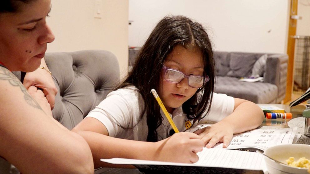 PHOTO: Fourth grader Yara Valerio and her mother Emma Mercado work through Yara's remaining summer homework on her first day of school.