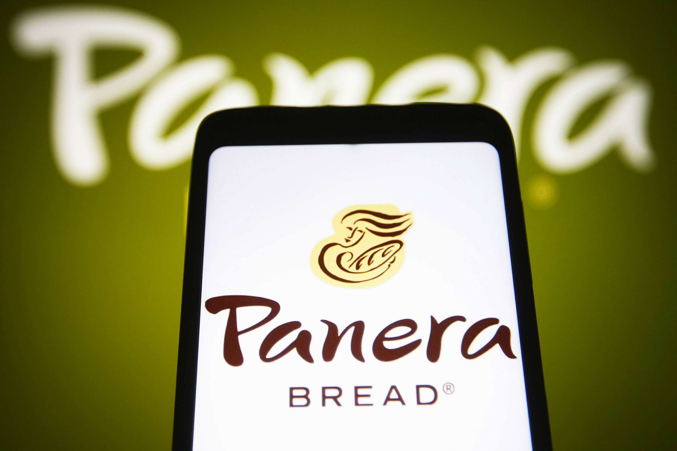 PHOTO: In this photo illustration, a Panera Bread Company logo is seen on a smartphone screen and in the background.
