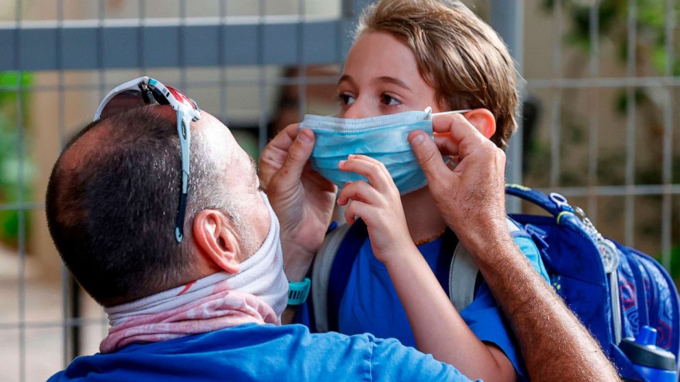 PHOTO: An father adjusts the face mask of his daughter on the first day of school, during the coronavirus pandemic, in the Israeli coastal city of Tel Aviv on Sept. 1, 2020.