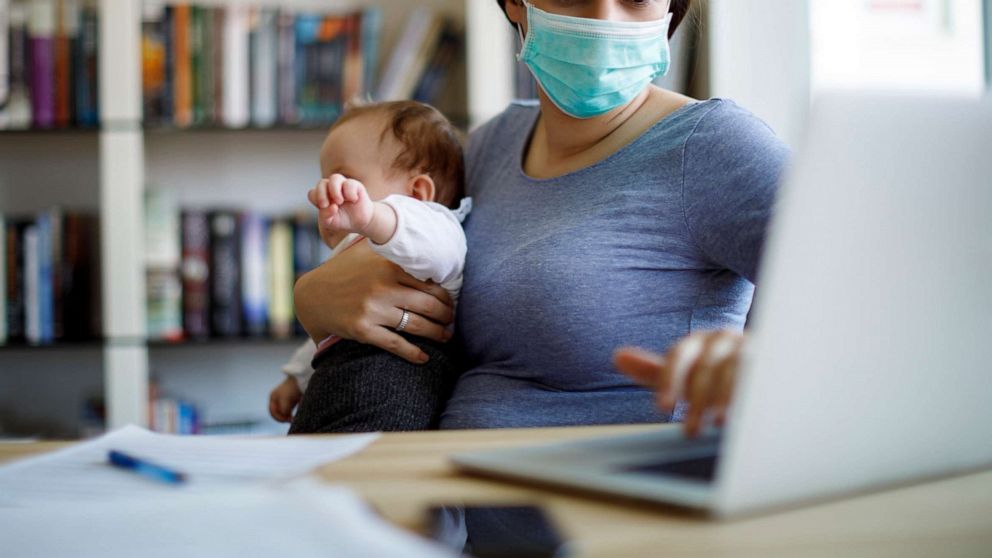 PHOTO: Mother with face protective mask working from home in an undated stock photo.