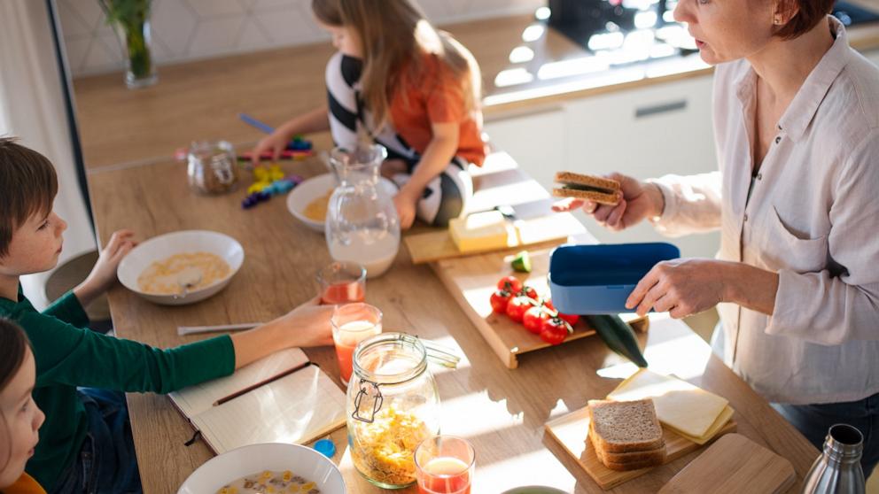PHOTO: Mother of three little children preparing breakfast in kitchen at home.