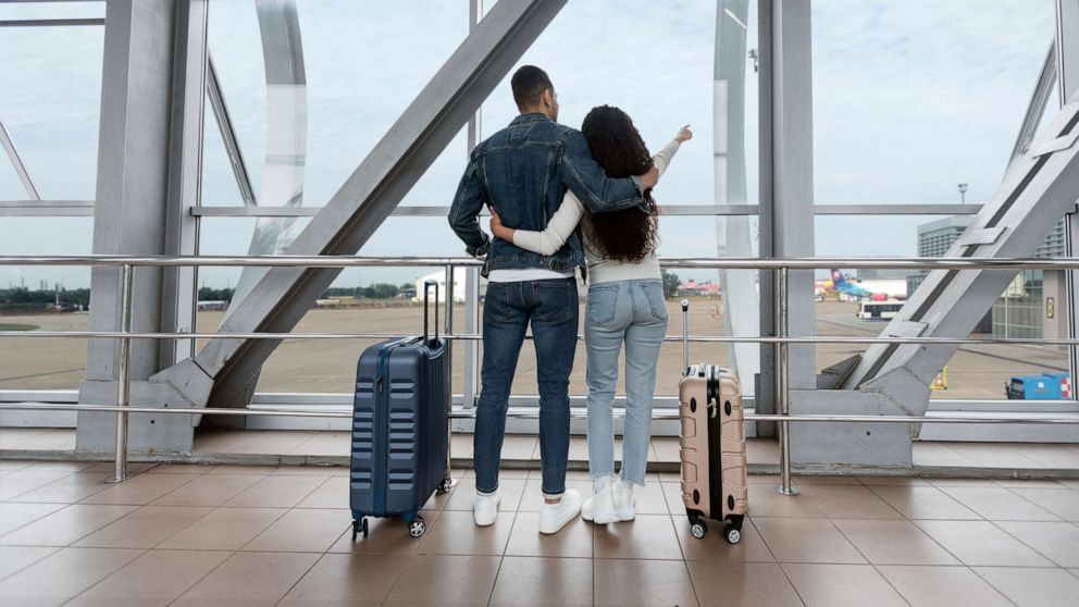 PHOTO: Stock image of a couple standing with suitcases at a terminal and looking at the window in an airport.