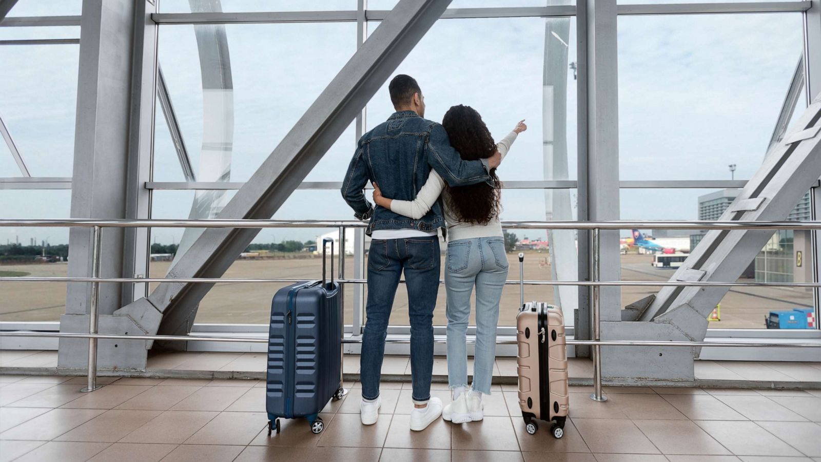 PHOTO: Stock image of a couple standing with suitcases at a terminal and looking at the window in an airport.