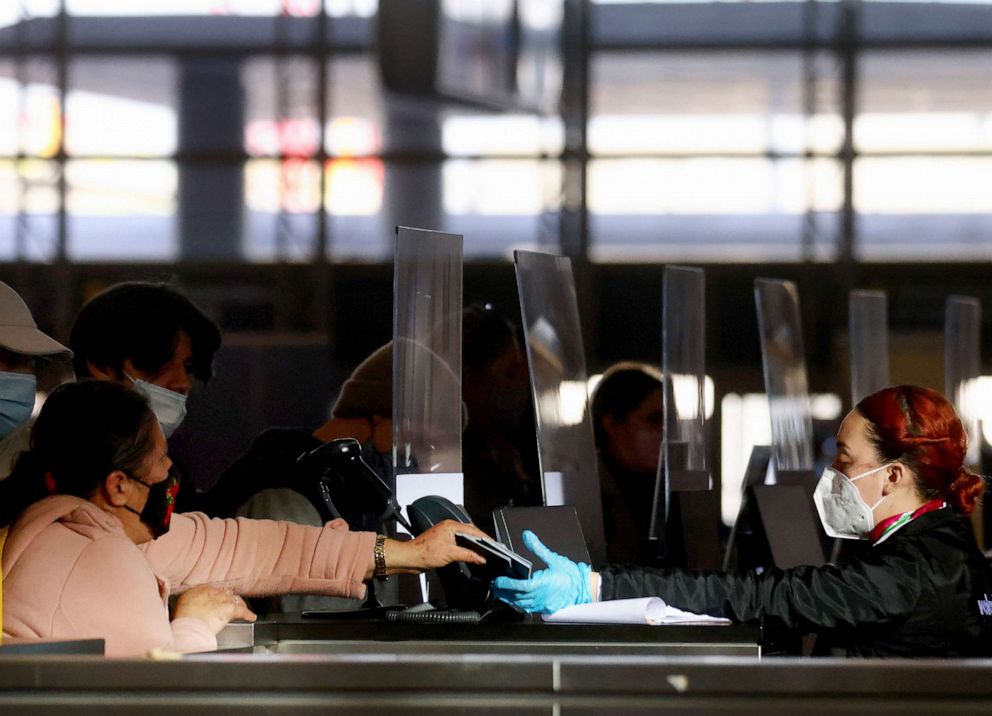 PHOTO: A traveler hands passports to an airline agent while checking in at the international terminal at Los Angeles International Airport (LAX) amid a surge in Omicron variant cases, Dec. 21, 2021, in Los Angeles.