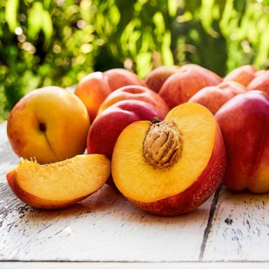 PHOTO: Ripe peaches with leaves on the old wooden table.