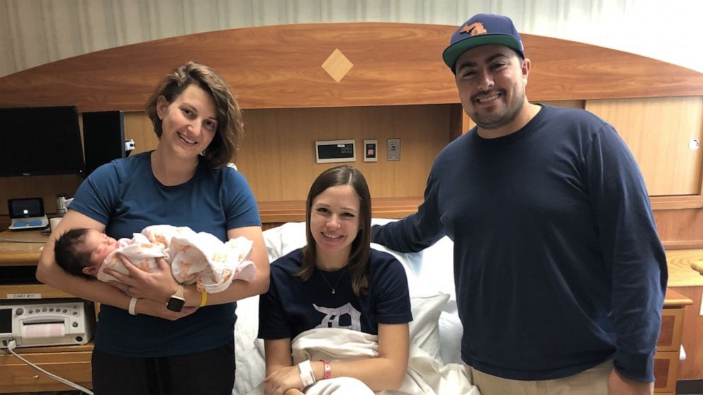 Katy Sanchez and her husband join Christy Acevo’s family for a photo. Both families are forever bonded after Acevo became the surrogate for Sanchez’s baby. 