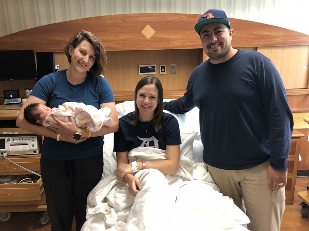 Katy Sanchez and her husband join Christy Acevo’s family for a photo. Both families are forever bonded after Acevo became the surrogate for Sanchez’s baby. 