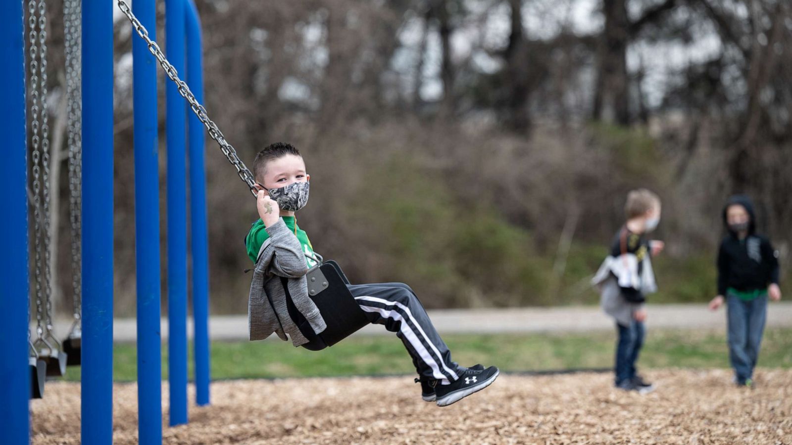 PHOTO: A child swings on a swing set while others play nearby during socially distanced recess on the playground of Medora Elementary School on March 17, 2021, in Louisville, Ky.