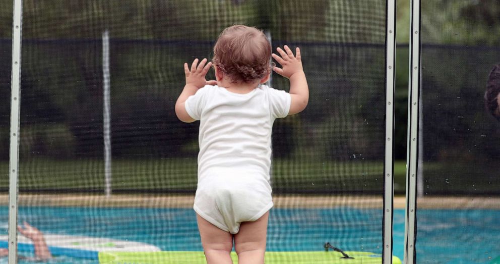 PHOTO: An infant child leans on a protective swimming pool fence or barrier in an undated stock photo.  