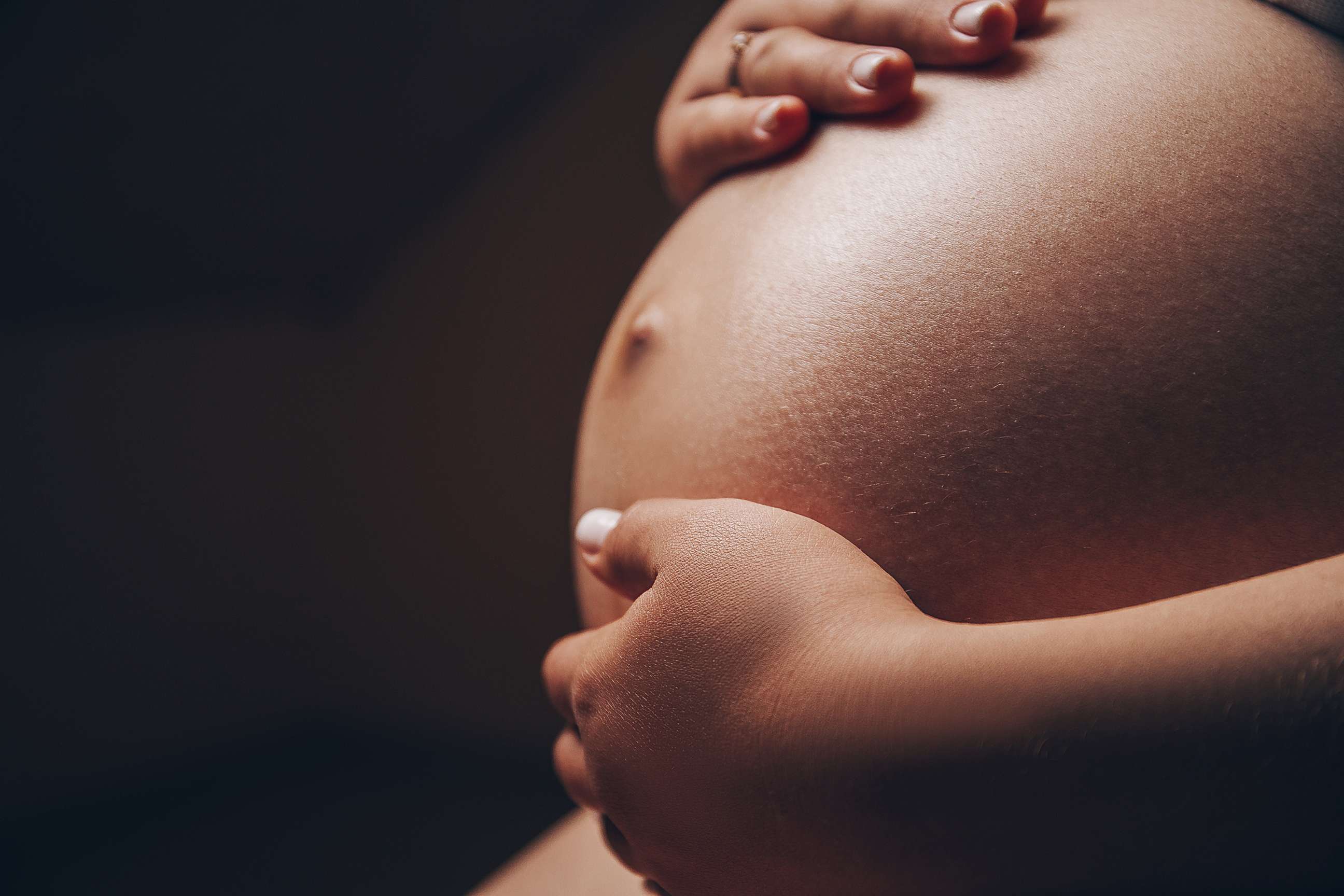 PHOTO: A pregnant woman of color holds her belly in an undated stock photo.