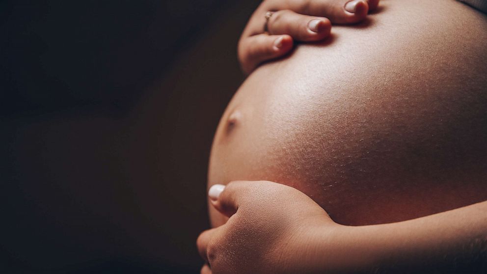 PHOTO: A pregnant woman of color holds her belly in an undated stock photo.