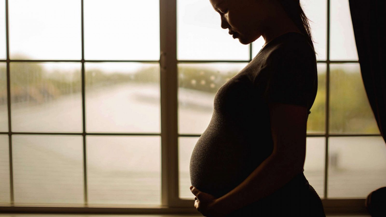 PHOTO: Stock photo of a pregnant woman standing by a window.