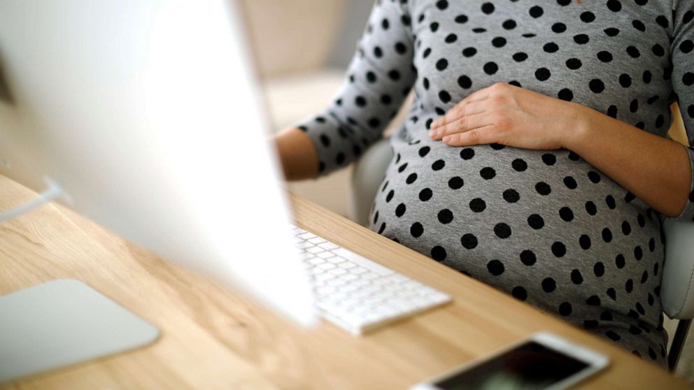 PHOTO: A pregnant woman works at an office.