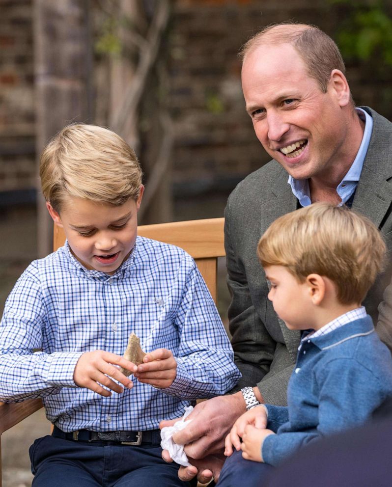 PHOTO: Prince William, Duke of Cambridge with his sons, Prince Louis and Prince George who is holding a tooth of a giant shark given to him by Sir David Attenborough in the gardens of Kensington Palace in London.