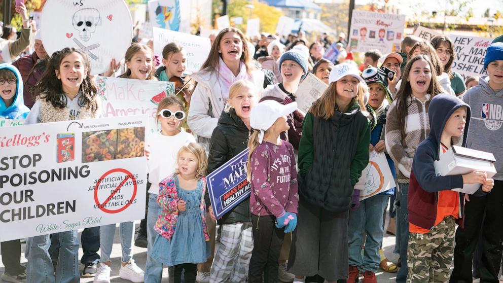 PHOTO: Children stand in front of protesters at Kellogg's headquarters in Battle Creek on Oct. 15, 2024 following a rally and march in protest of artificial food dyes and preservatives in cereal.