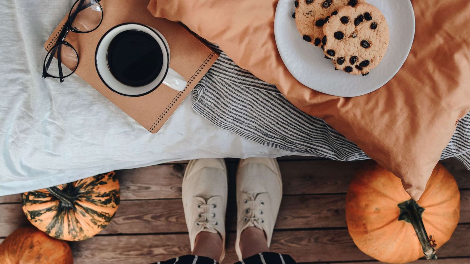 PHOTO: A person looks down at a cozy spot with coffee, treats and pumpkins.