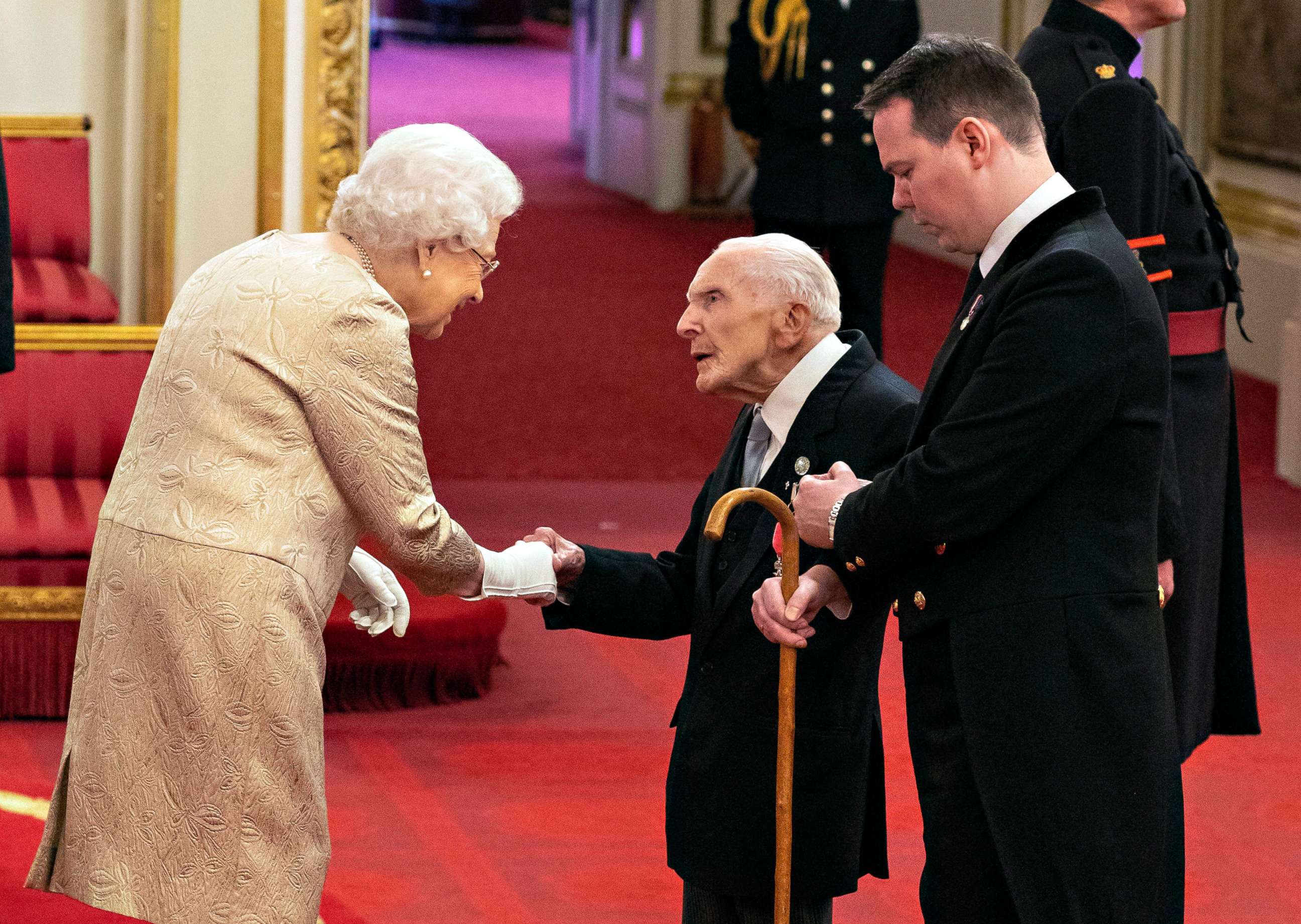 PHOTO: Queen Elizabeth wears gloves as she awards the MBE (Member of the Order of the British Empire) to Harry Billinge from St Austell, during an investiture ceremony at Buckingham Palace in London, March 3, 2020.