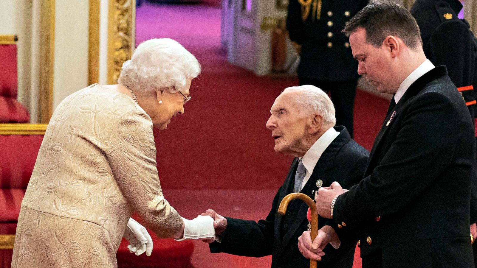 PHOTO: Queen Elizabeth wears gloves as she awards the MBE (Member of the Order of the British Empire) to Harry Billinge from St Austell, during an investiture ceremony at Buckingham Palace in London, March 3, 2020.