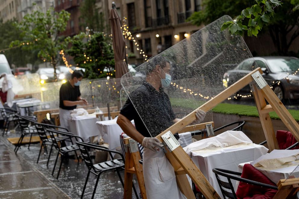 PHOTO: A restaurant employee picks up a plastic partition while cleaning up after the rain in New York, Aug. 25, 2020.