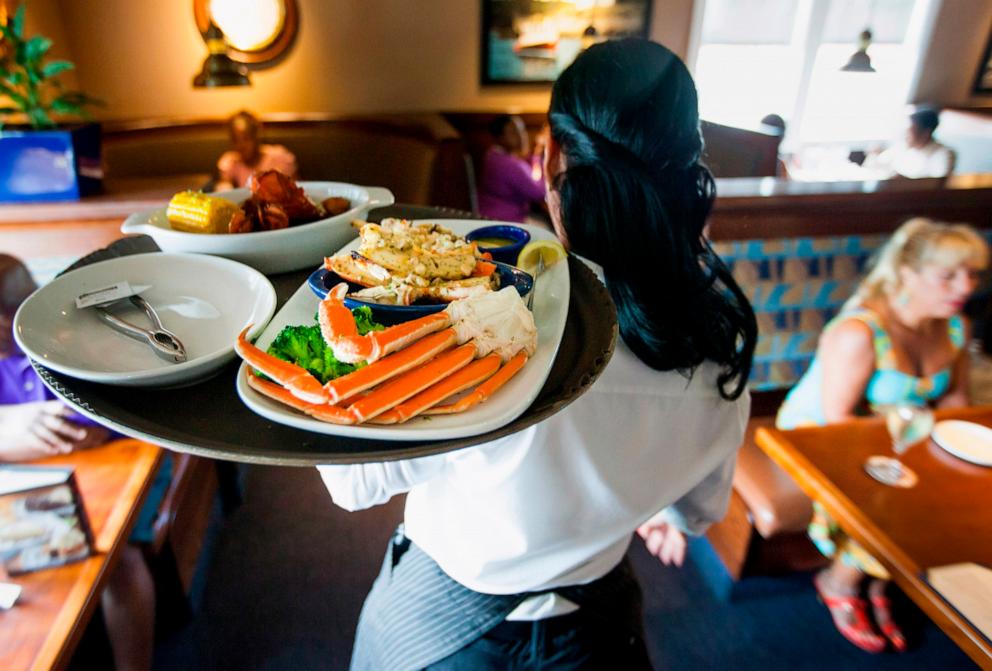 PHOTO: A waitress carries a tray a lobster kettle and a crab trio dish at a Red Lobster restaurant in Yonkers, New York, July 24, 2014.