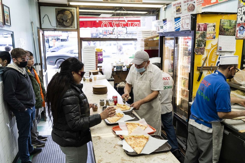 PHOTO: A worker serves pizza to a customer at the Pizza Palace restaurant in the Inwood neighborhood of New York, 
on March 26, 2022.