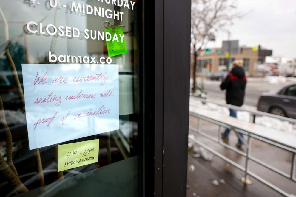 PHOTO: A sign in the window at Bar Max reads, We are currently seating customers with proof of vaccination, on April 16, 2021, in Denver.