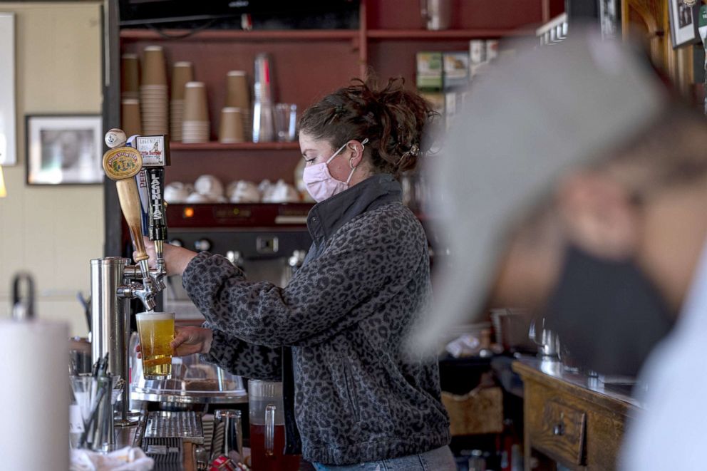 PHOTO: A worker wearing a protective mask pours a beer inside a restaurant in San Francisco, May 6, 2021.