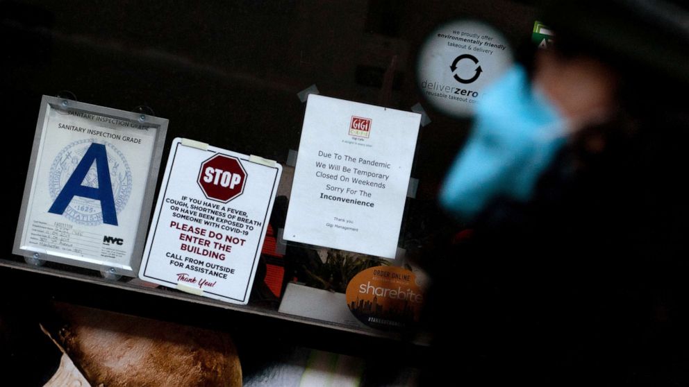 PHOTO: A person walks past a sign reading "Due to the pandemic, we will be closed on weekdays" displayed at a restaurant, Jan. 12, 2022, in New York City. 