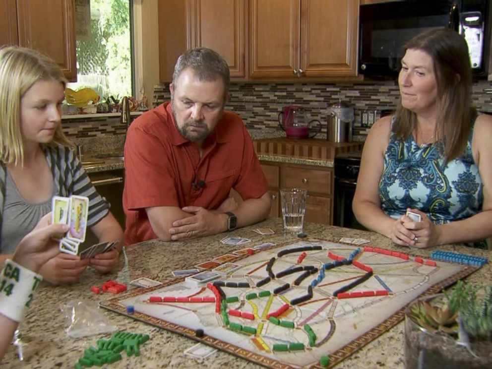 PHOTO: Carl and Mindy Jensen play a board game with their two children.