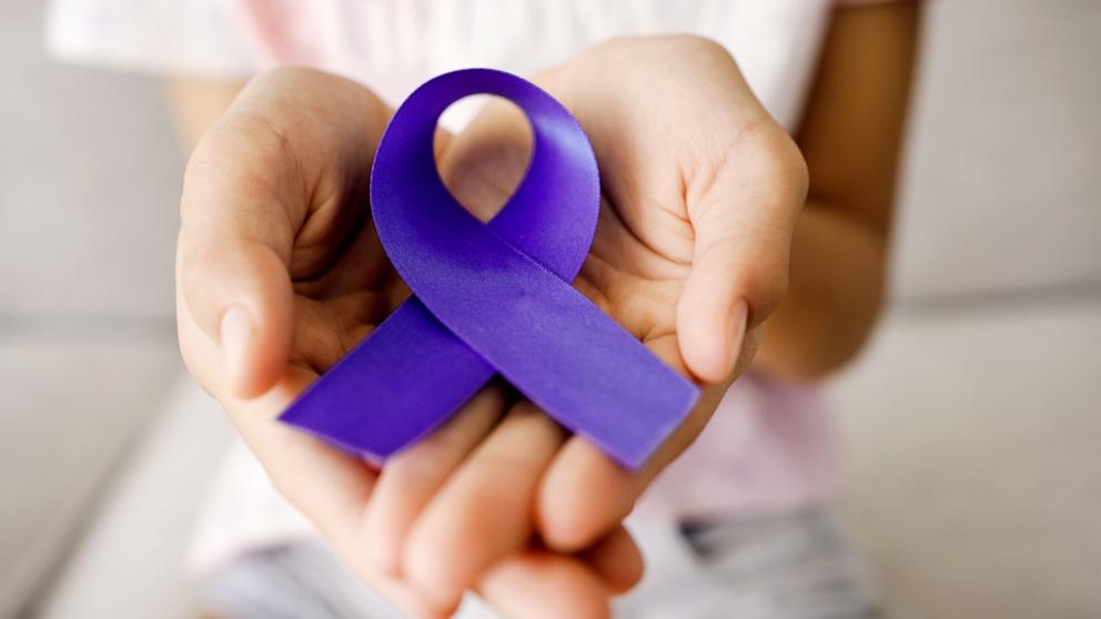 PHOTO: Stock image of hands holding a purple ribbon.
