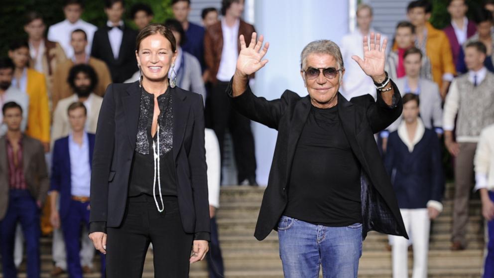 PHOTO: Fashion designer Roberto Cavalli and his wife Eva acknowledge the audience after the Roberto Cavalli Spring-Summer 2012 Menswear collection, June 18, 2011, during the Men's fashion week in Milan. 