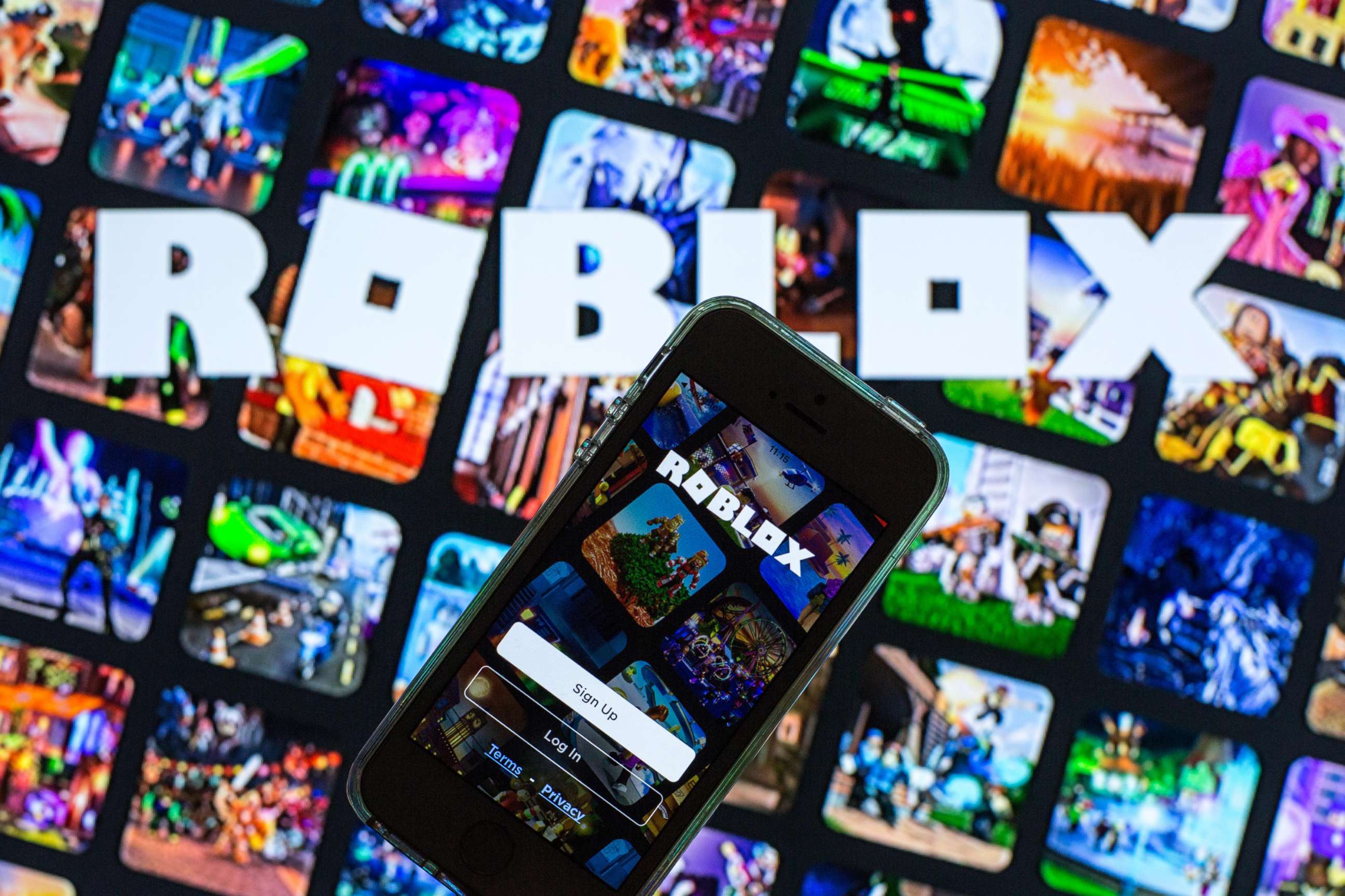 PHOTO: The Roblox app seen displayed on a smartphone screen and a Roblox logo in the background in this photo illustration, March 30, 2021.