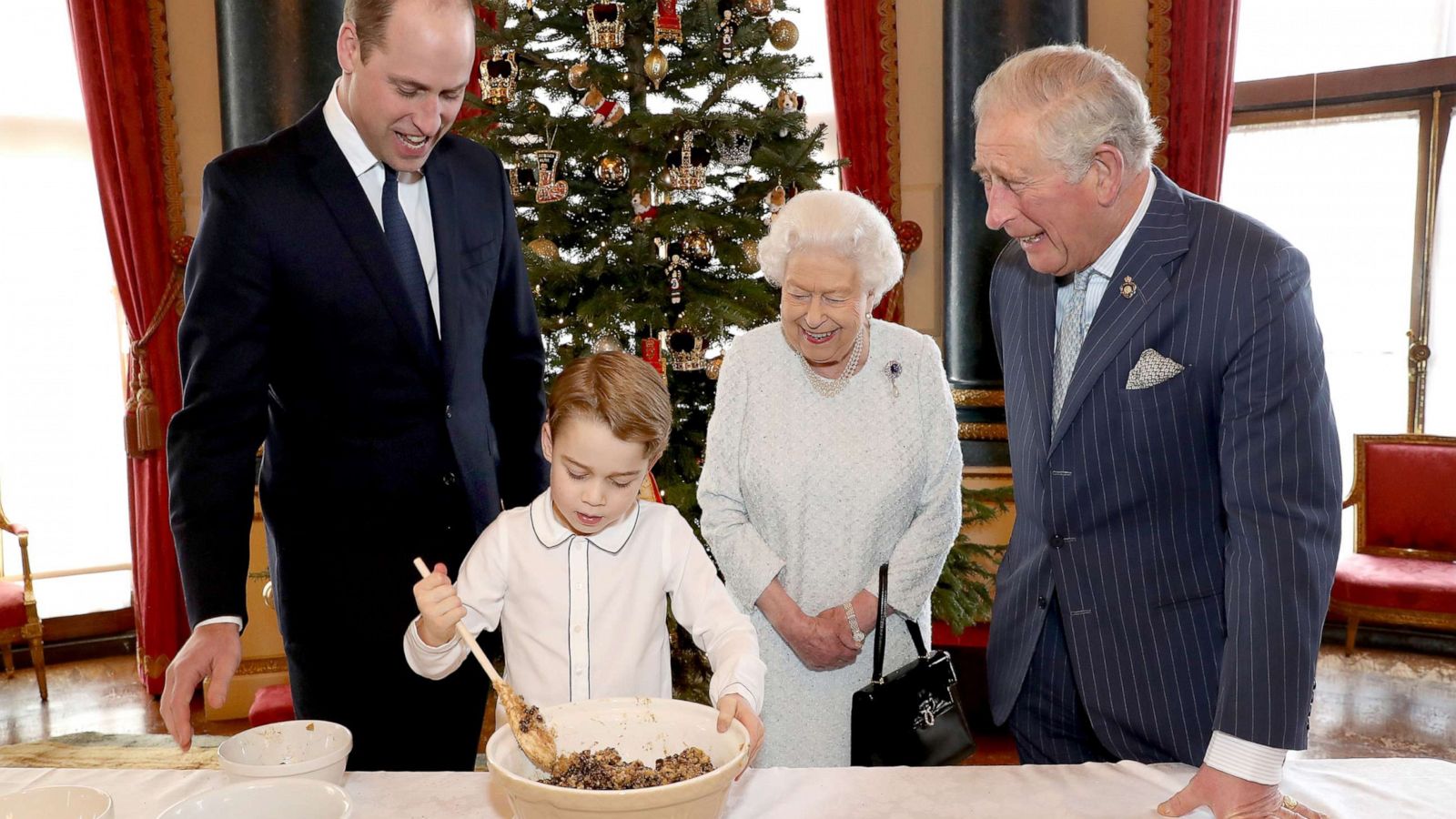 PHOTO: An undated photo released by Buckingham Palace, Prince William, Duke of Cambridge, Prince George, Queen Elizabeth II and Prince Charles, Prince of Wales prepare special Christmas puddings in the Music Room at Buckingham Palace in London.