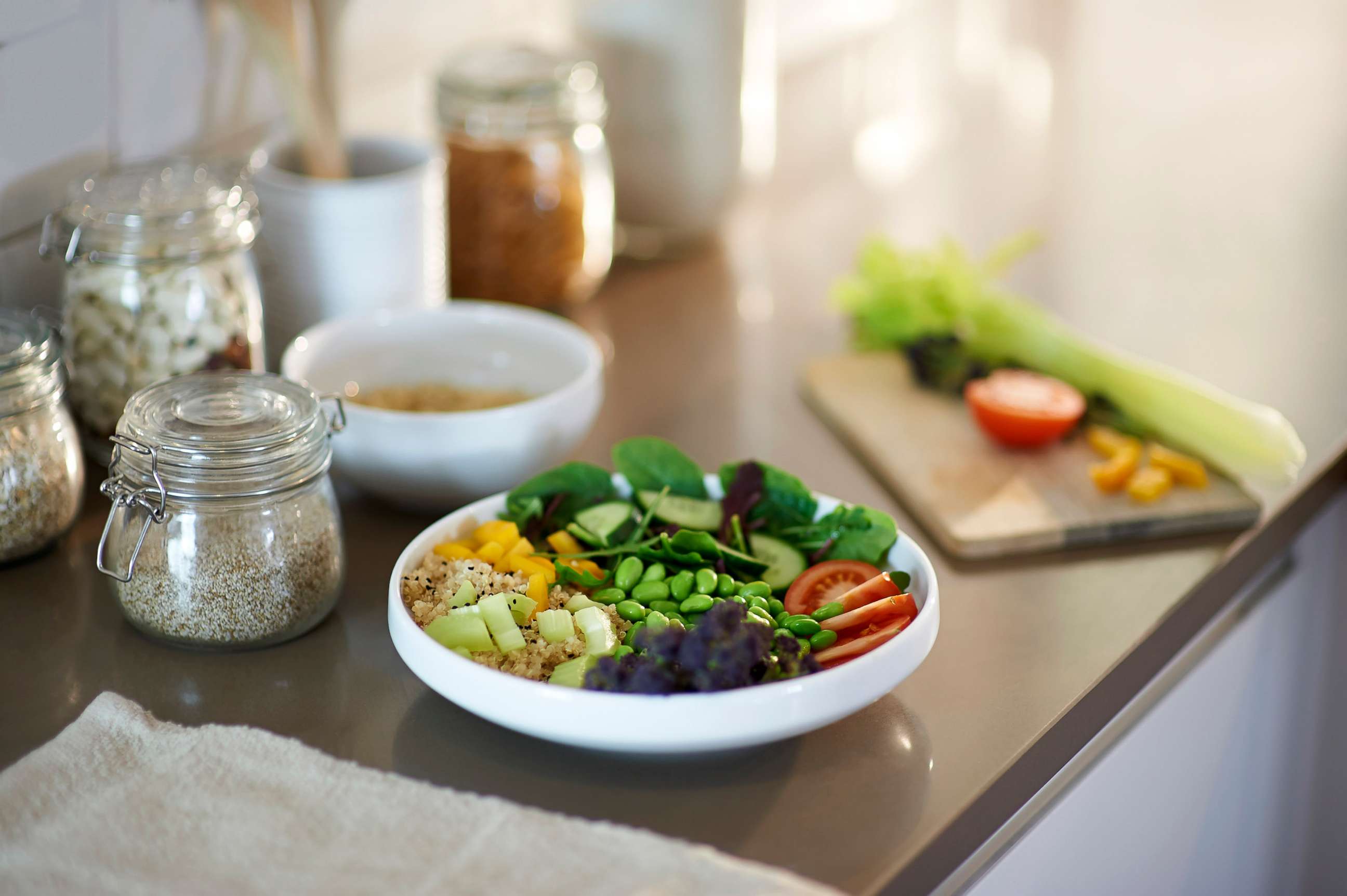 PHOTO: A vegan salad bowl of quinoa, peppers, spinach, soya beans, tomatoes, cucumber, purple sprouting broccoli is placed on a kitchen counter. 