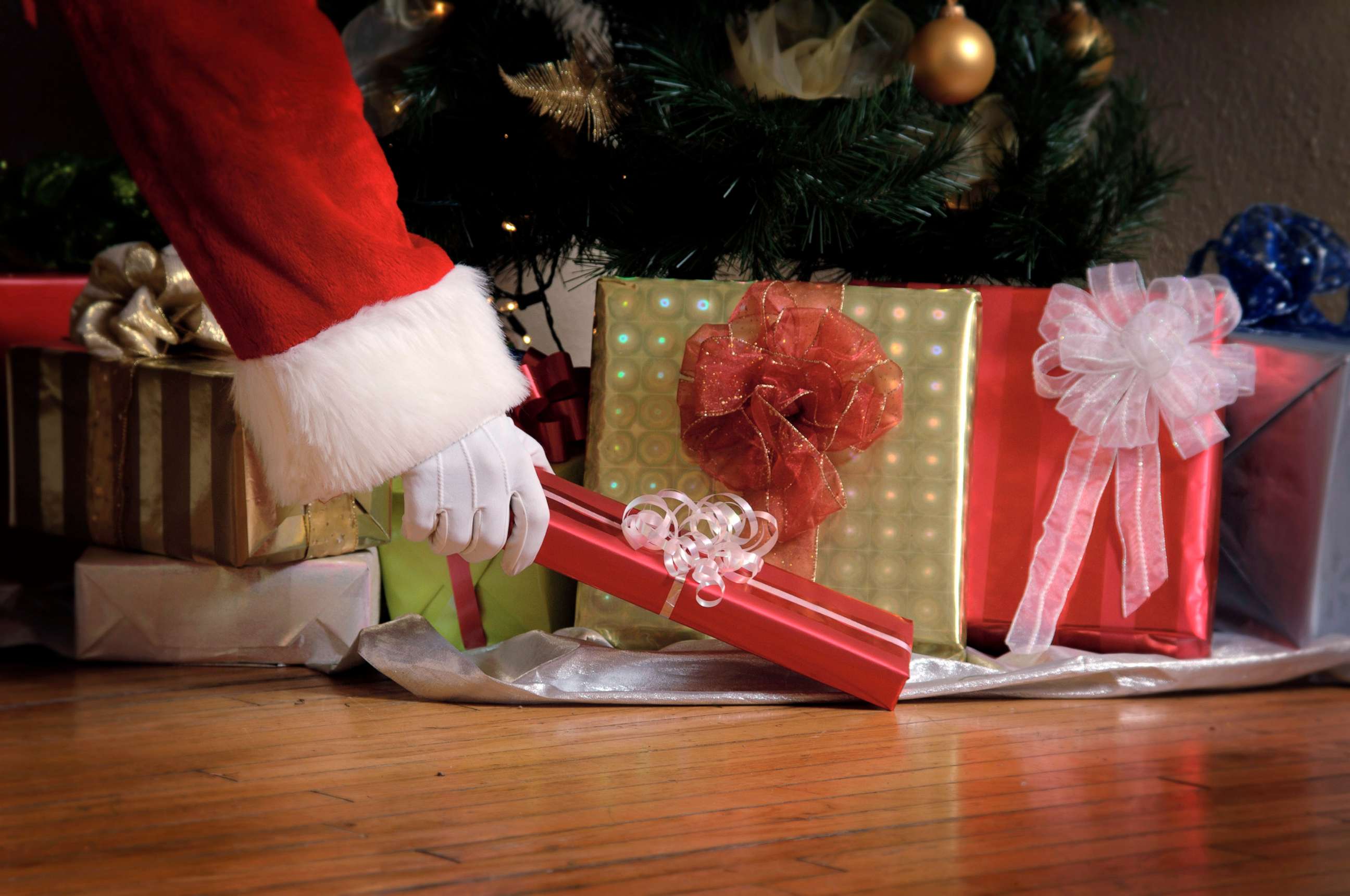 PHOTO: Santa puts a gift under a Christmas tree.