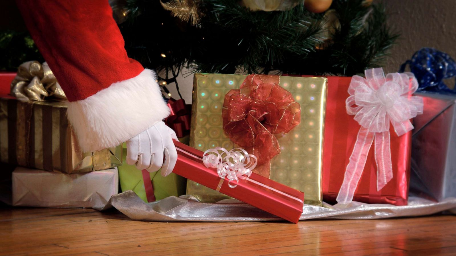 PHOTO: Santa puts a gift under a Christmas tree.